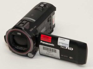 Schwarzer Panasonic HC-V777 Camcorder mit aufgeklapptem Display, auf dem Aufkleber mit Text und Barcode sichtbar sind.