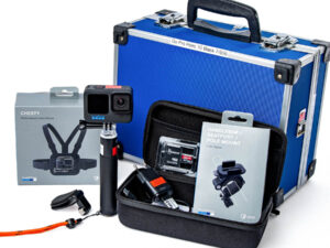 Schwarze GoPro Hero 10 Black Actionkamera auf Halterung mit sichtbarem Objektiv und blauer Beschriftung. Zusammenstellung des Zubehörs und des Transportkoffers