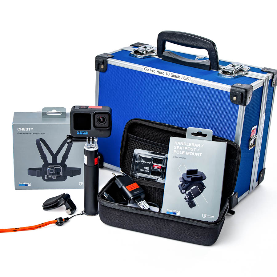 Schwarze GoPro Hero 10 Black Actionkamera auf Halterung mit sichtbarem Objektiv und blauer Beschriftung. Zusammenstellung des Zubehörs und des Transportkoffers