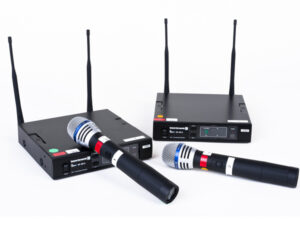 Zwei schwarze Funkmikrofone Opus 300 mit silbernen Köpfen und roten Ringen liegen vor zwei schwarzen Empfängern mit Antennen und Displays.