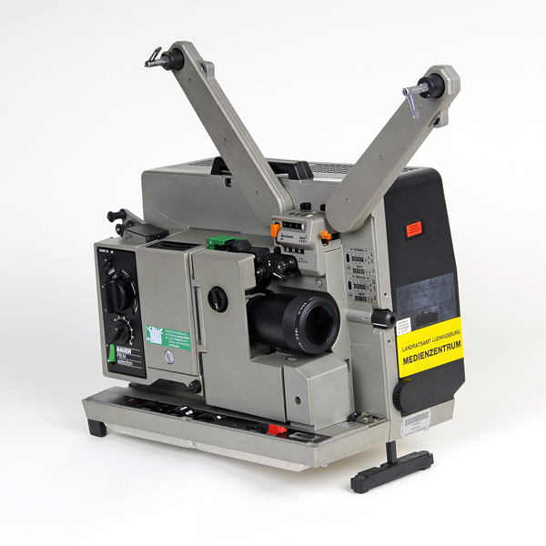 Graue 16-mm-Filmkprojektor mit zwei leeren Filmspulenarmen, Objektiv und mehreren Einstellknöpfen.