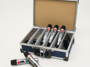 Offener blauer Koffer mit gepolstertem Innenraum, darin sechs silberne Mikrofone mit schwarzen Köpfen, zwei Mikrofone liegen davor.