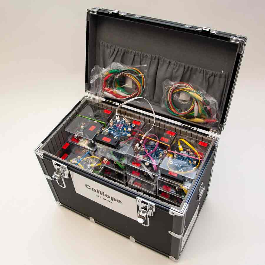 Offener schwarzer Transportkoffer mit mehreren transparenten Kunststoffboxen, darin elektronische Platinen und bunte Kabel, zwei Kabelbündel in Plastiktüten im Deckel, Aufkleber mit 'Calliope' am Koffer.