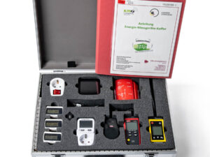 Offener Koffer mit Schaumstoffeinlage, darin mehrere Energie-Messgeräte, Steckdosenadapter und eine rote Anleitung mit dem Titel 'Anleitung Energie-Messgeräte-Koffer'.