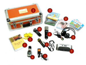 Orangener Ohrenspitzerkoffer mit silbernen Kanten und Griff, umgeben von nummerierten Gegenständen wie Mikrofonen, Kopfhörern, CDs, Notizbuch und elektronischen Geräten.