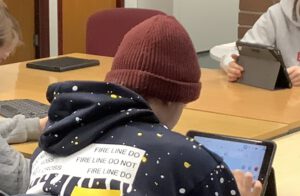 Jugendlicher arbeitet an einem Tablet, Ansicht von Hinten