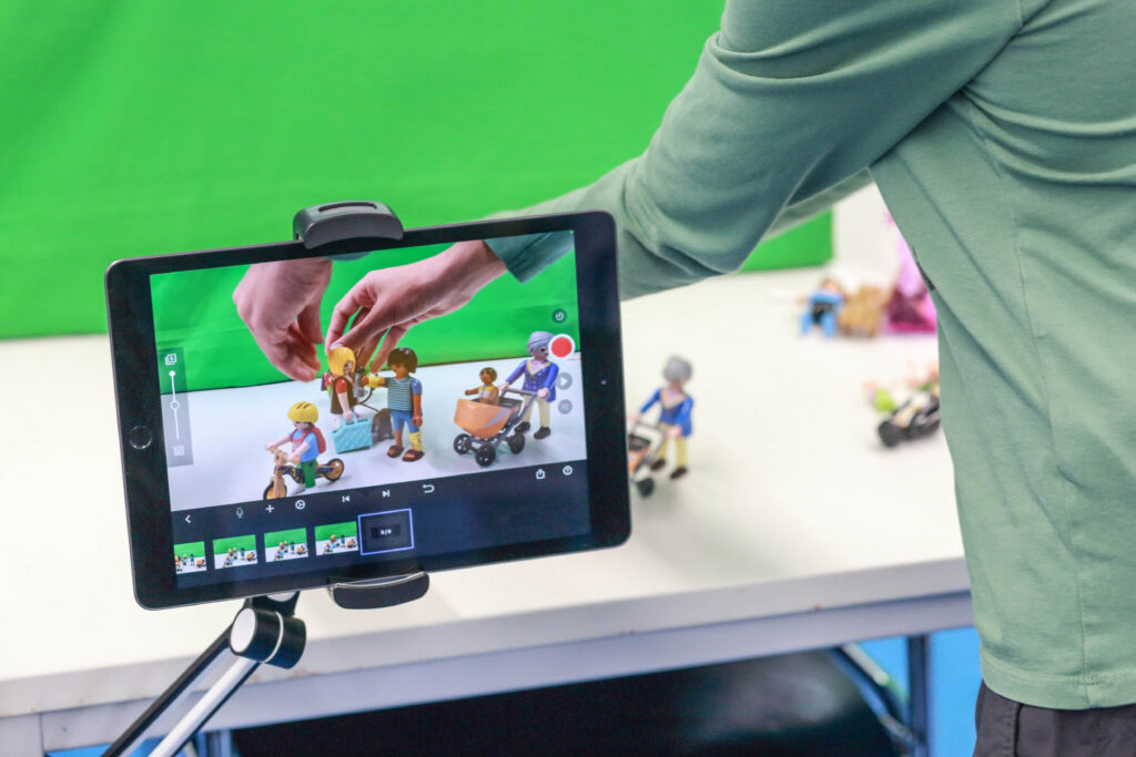 Bild von einem iPad vor einem Greenscreen, das Playmobilmännchen im Display zeigt.